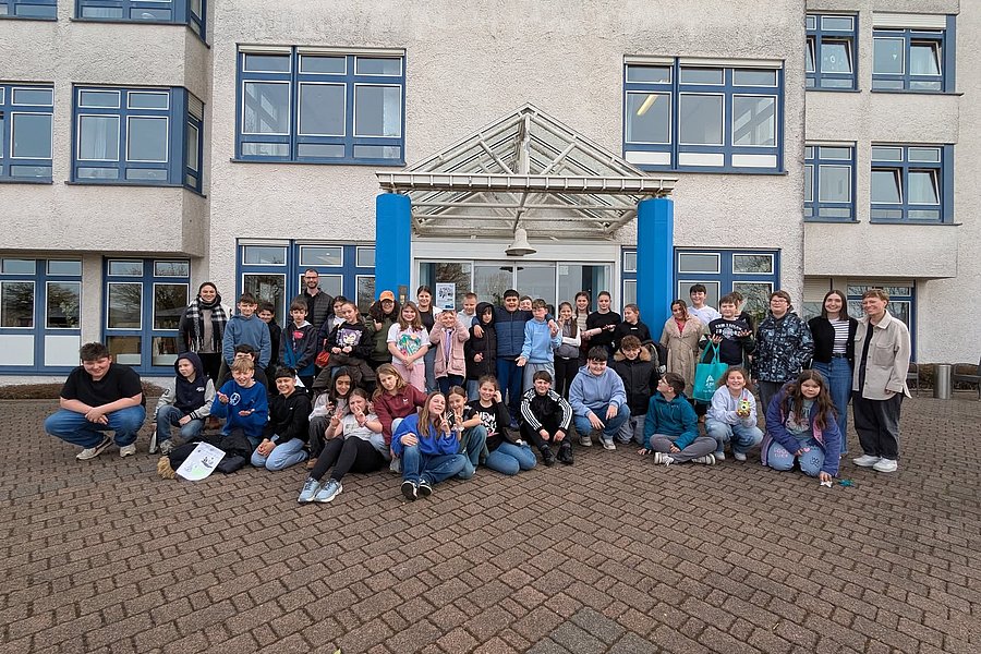 Gruppenfoto von Schülern vor einem modernen Gebäude mit großen Fenstern.